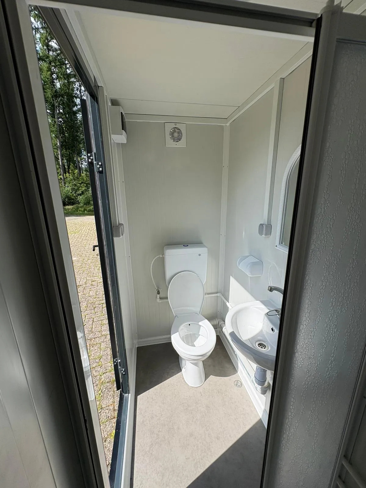 Interior of a portable bathroom unit with toilet and sink.
