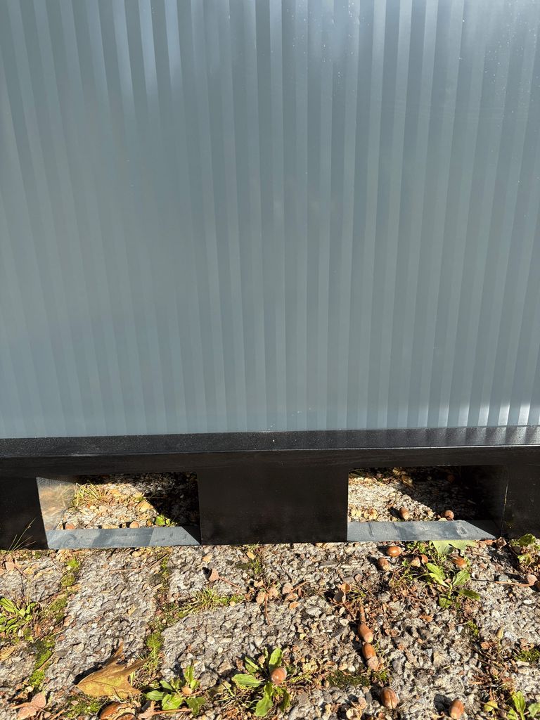 Forklift slots at the base of a portable toilet unit for camping.