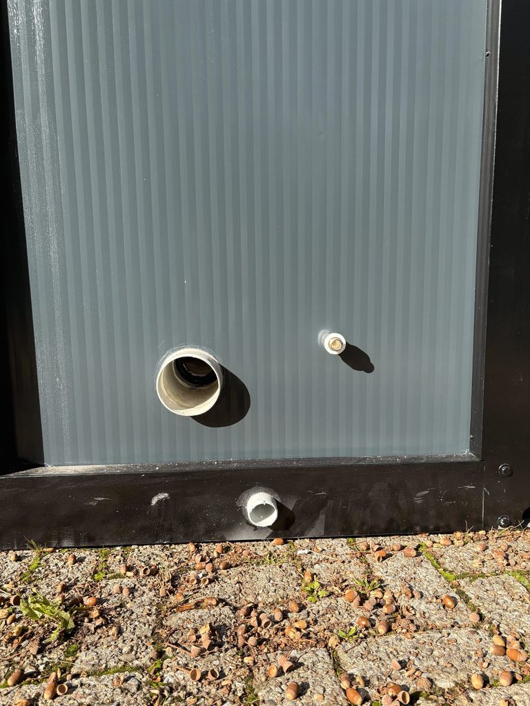 Front view of sewer and water connections on a portable toilet unit for camping.